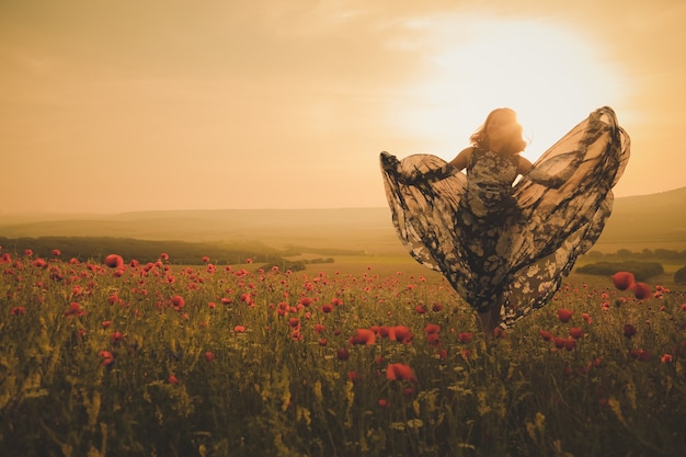 Foto jovem mulher bonita no campo de primavera, caminhando no campo de papoulas incrível.