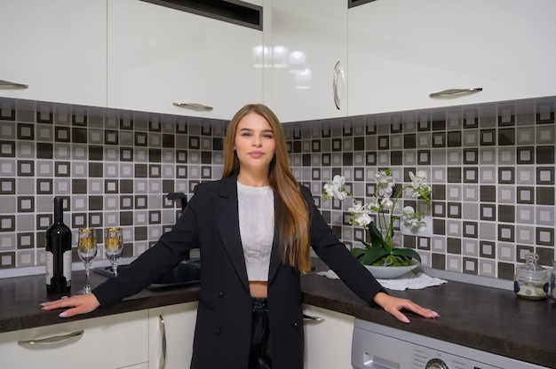 Jovem mulher bonita no interior luxuoso da cozinha moderna em preto e branco com design clean