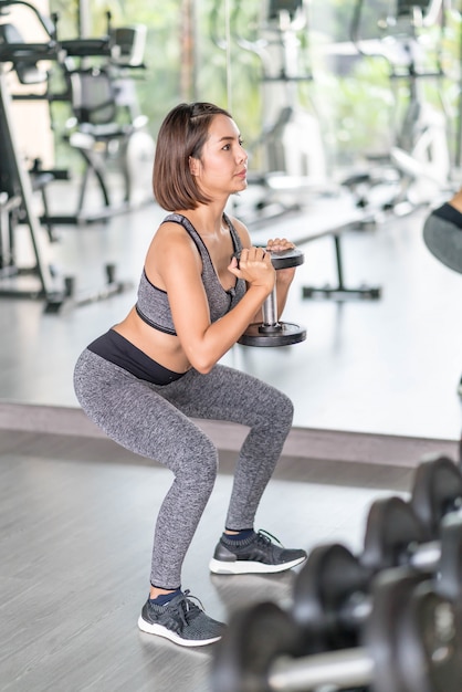 Jovem mulher bonita no sportswear malhando na academia