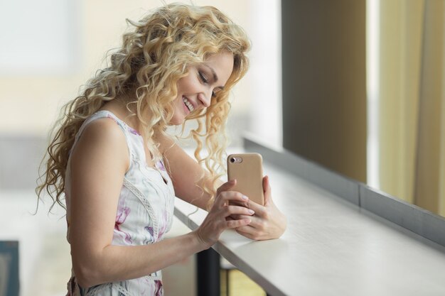 Jovem mulher bonita no vestido faz foto smartphone no café.