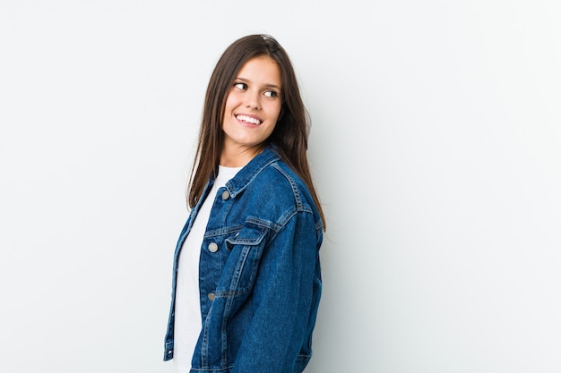 Jovem mulher bonita olha de lado sorrindo, alegre e agradável.