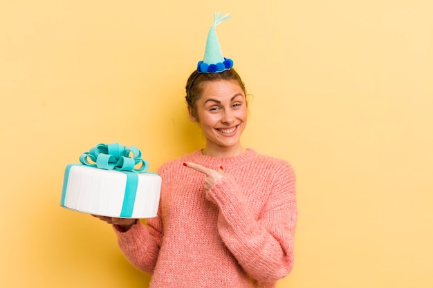 Jovem mulher bonita olhando animada e surpresa apontando para o conceito de aniversário lateral