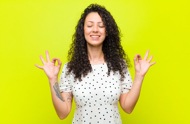 Jovem mulher bonita olhando concentrado e meditando, sentindo-se satisfeito e relaxado, pensando ou fazendo uma escolha sobre a parede de croma