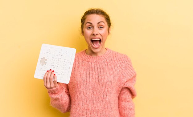 Jovem mulher bonita olhando o conceito de quebra-cabeça feliz e agradavelmente surpreso