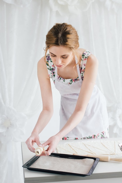 Jovem mulher bonita preparando croissants caseiros