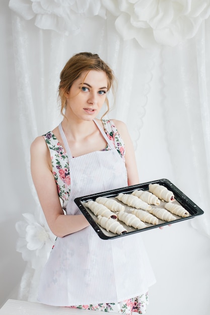 Jovem mulher bonita preparando croissants caseiros