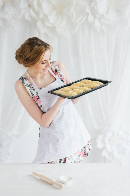 Jovem mulher bonita preparando croissants caseiros