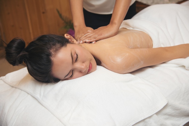 Jovem mulher bonita que obtém o salão de beleza da massagem dos termas.