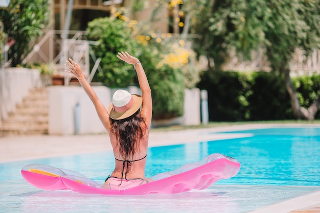 Jovem mulher bonita que relaxa na piscina.