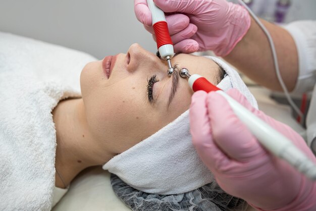 Foto jovem mulher bonita recebendo tratamento facial de estimulação por microcorrentes em uma clínica de spa procedimento para suavizar rugas