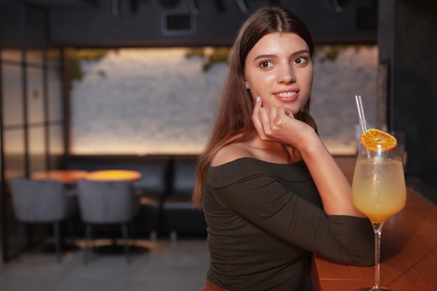 Jovem mulher bonita relaxante no bar, tomar um cocktail, copie o espaço