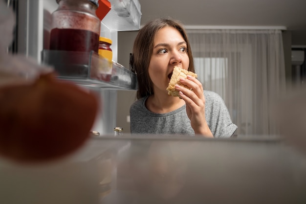 Jovem mulher bonita rouba comida fria à noite