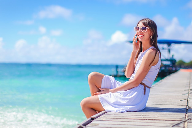 Jovem mulher bonita se divertindo na beira-mar tropical. Menina feliz o céu azul e a água turquesa no mar na ilha do Caribe