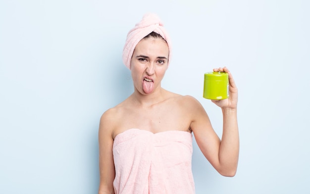 Jovem mulher bonita se sentindo enojada e irritada e língua para fora do chuveiro e conceito de produto de cabelo