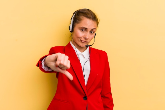 Jovem mulher bonita se sentindo mostrando os polegares para baixo o conceito de operador de telemarketing