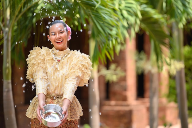Foto jovem mulher bonita se veste com belos trajes tailandeses espirrando água nos templos e preserva a boa cultura do povo tailandês durante o festival songkran dia da família do ano novo tailandês em abril