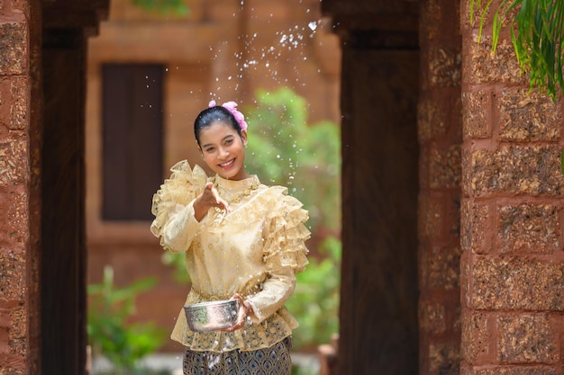 Jovem mulher bonita se veste com belos trajes tailandeses espirrando água nos templos e preserva a boa cultura do povo tailandês durante o festival Songkran Dia da Família do Ano Novo Tailandês em abril