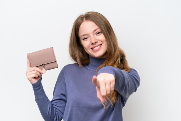 Jovem mulher bonita segurando carteira isolada no fundo branco aponta o dedo para você com uma expressão confiante