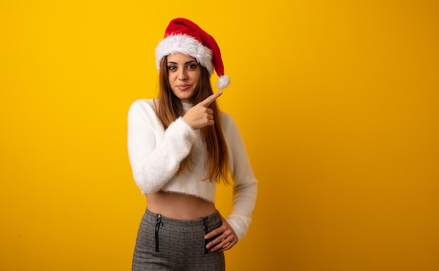 Jovem mulher bonita segurando o presente sorrindo e apontando para o lado