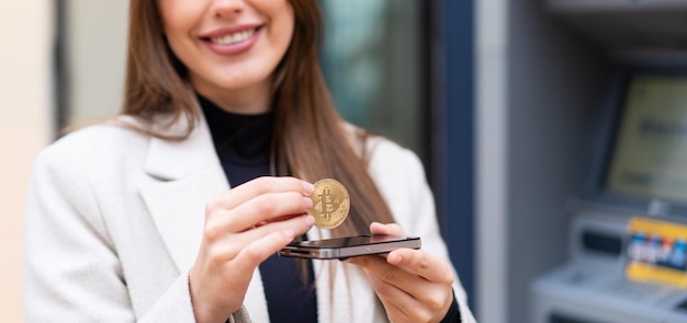 Jovem mulher bonita segurando um bitcoin ao ar livre