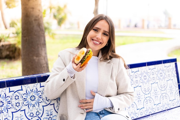 Jovem mulher bonita segurando um hambúrguer ao ar livre