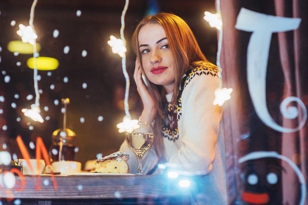 Jovem mulher bonita sentada no café, bebendo vinho. Natal, ano novo, dia dos namorados, férias de inverno