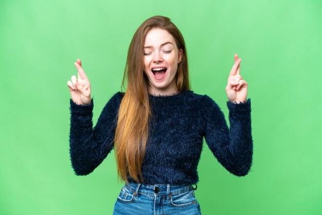 Jovem mulher bonita sobre fundo croma chave isolado com dedos cruzando