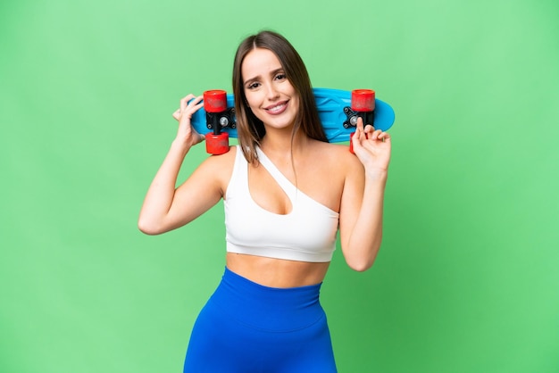 Jovem mulher bonita sobre fundo croma chave isolado com um skate