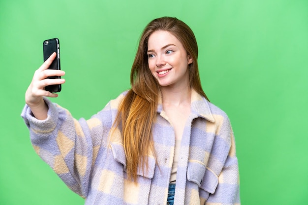 Jovem mulher bonita sobre fundo croma chave isolado fazendo uma selfie