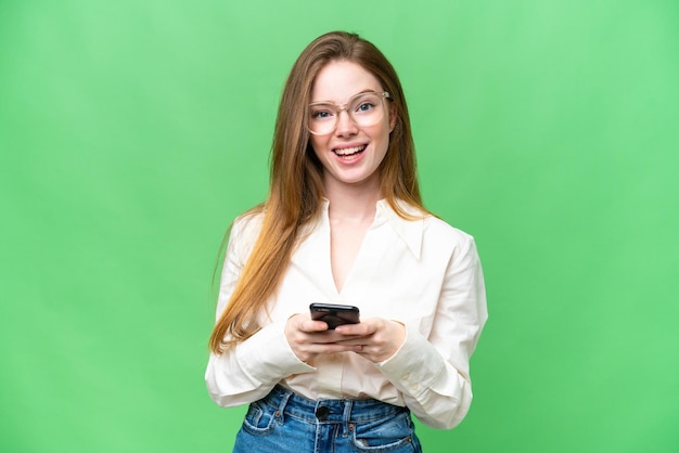 Jovem mulher bonita sobre fundo croma isolado surpreso e enviando uma mensagem