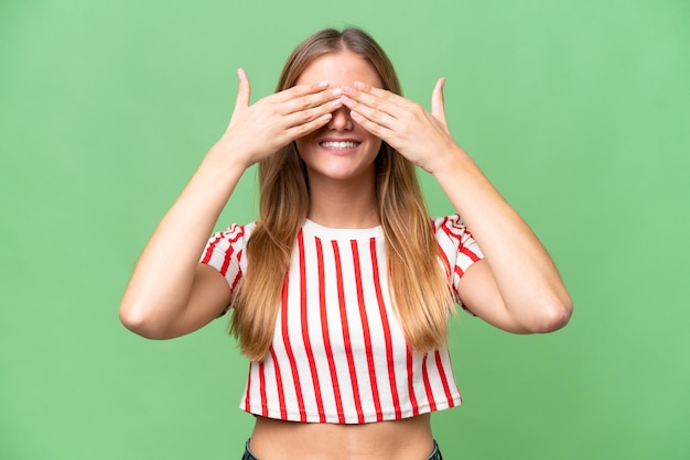 Jovem mulher bonita sobre fundo isolado, cobrindo os olhos com as mãos e sorrindo