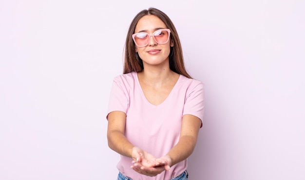 Jovem mulher bonita sorrindo alegremente com amigável e oferecendo e mostrando um conceito. conceito de óculos de sol rosa