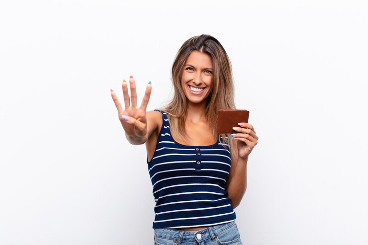 Foto jovem mulher bonita sorrindo e olhando amigável, mostrando o número quatro ou quarto com a mão para a frente, contando com uma carteira de couro.