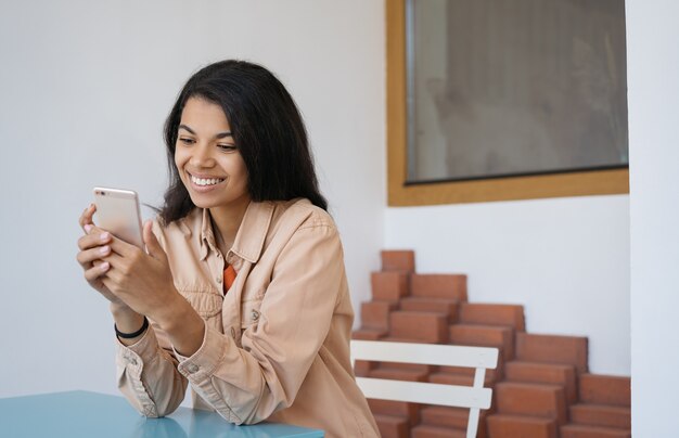 Jovem mulher bonita usando telefone celular, compras online, comunicação, bate-papo, sentado em um café