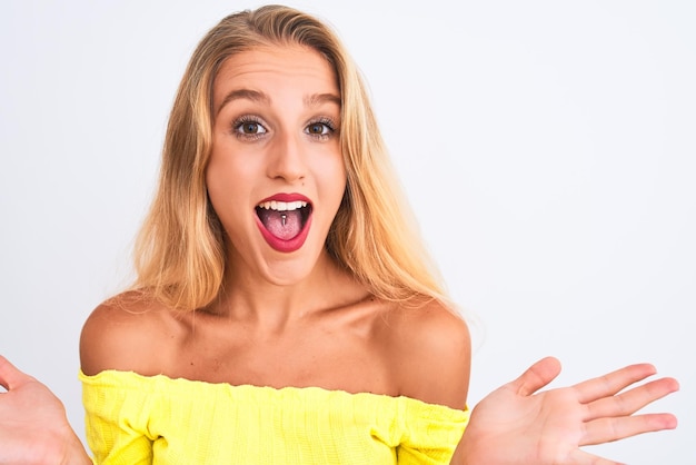 Jovem mulher bonita vestindo camiseta amarela em pé sobre fundo branco isolado expressão vencedora muito feliz e animada comemorando a vitória gritando com um grande sorriso e levantou as mãos