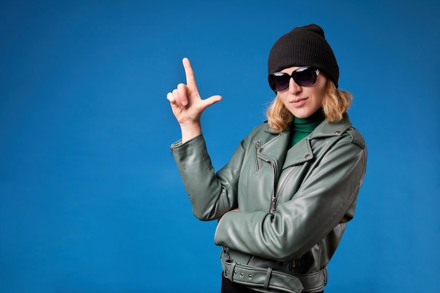 Jovem mulher bonita vestindo jaqueta casual sobre fundo azul isolado atirando com a mão e os dedos apontando para cima como arma