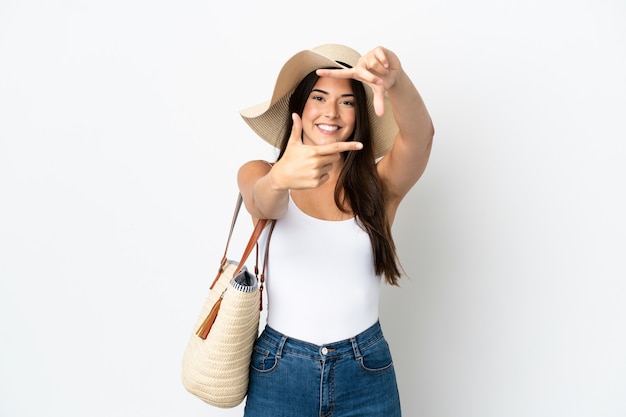 Jovem mulher brasileira com Pamela segurando uma bolsa de praia isolada no fundo branco focalizando o rosto. Símbolo de enquadramento