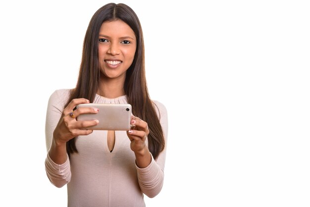 Jovem mulher brasileira feliz sorrindo enquanto tira foto com o celular