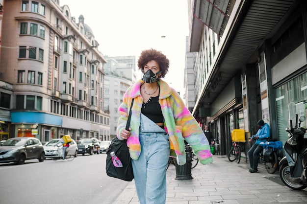 Foto jovem mulher caminhando ao ar livre em milão usando máscara médica, protegendo da poluição e vírus