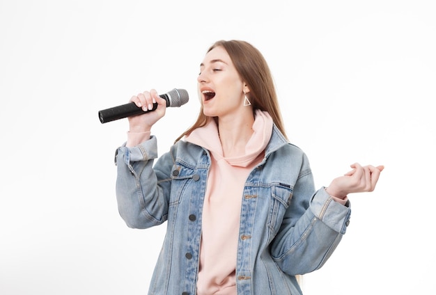 Jovem mulher caucasiana alegre cantando no microfone isolado no fundo branco