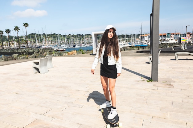 Jovem mulher caucasiana andando de longboard no calçadão