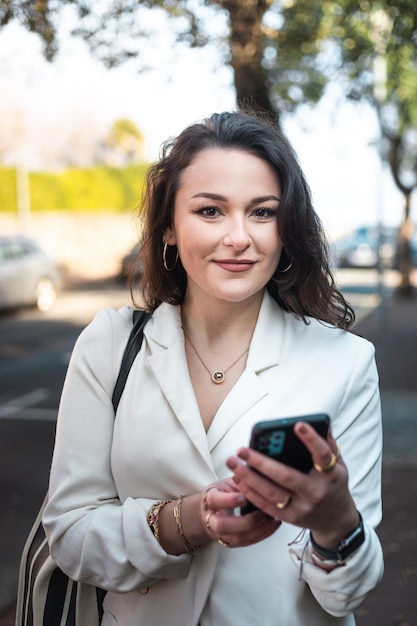 Jovem mulher caucasiana andando na rua usando um smartphone