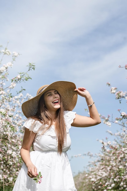 Jovem mulher caucasiana apreciando o florescimento de uma macieira rindo