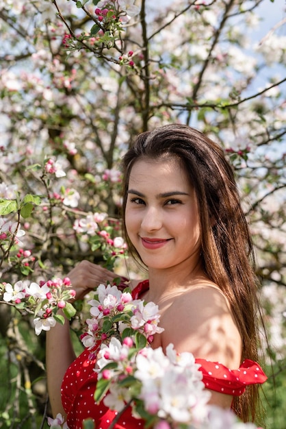 Jovem mulher caucasiana, apreciando o florescimento de uma macieira