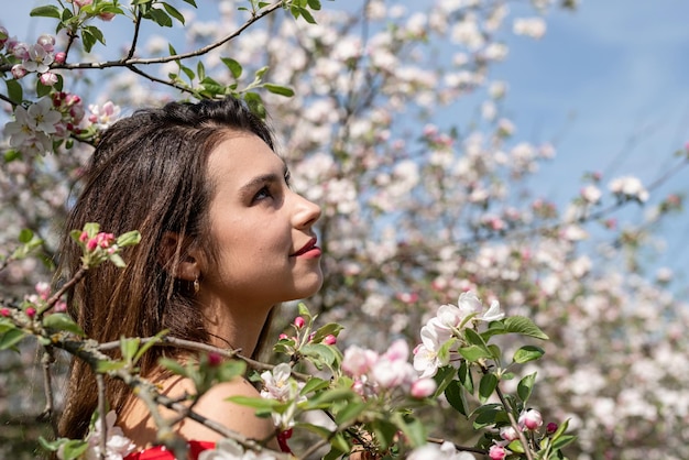 Jovem mulher caucasiana, apreciando o florescimento de uma macieira