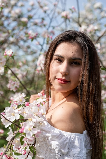 Jovem mulher caucasiana, apreciando o florescimento de uma macieira