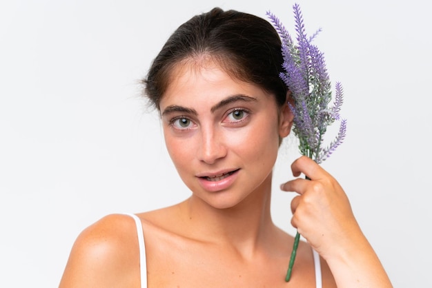 Jovem mulher caucasiana bonita isolada em fundo branco segurando uma planta de lavanda Retrato em close-up