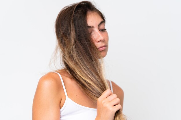 Jovem mulher caucasiana bonita isolada em fundo branco tocando seu cabelo Retrato em close-up