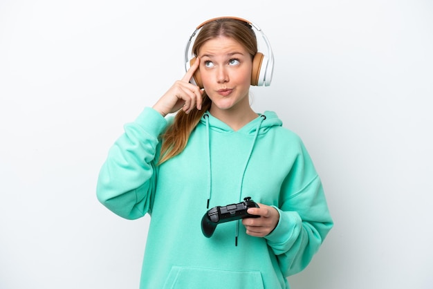 Jovem mulher caucasiana brincando com um controlador de videogame isolado no fundo branco com dúvidas e pensando