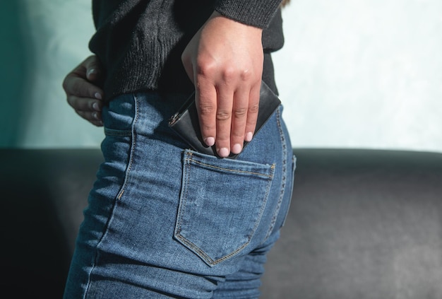 Jovem mulher caucasiana colocando carteira no bolso da calça jeans